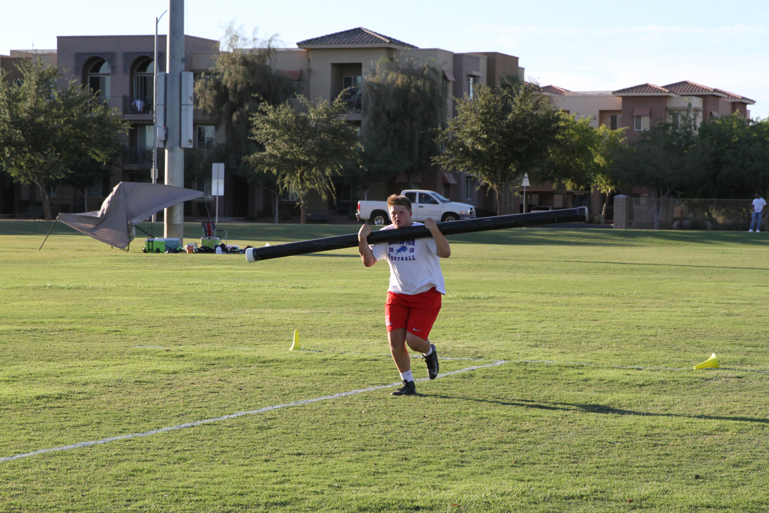 Football player carries a pole across a field